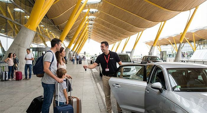 Conductor de Valet Barajas recibiendo a una familia junto a su veh&iacute;culo frente a la Terminal 4 del Aeropuerto de Madrid.