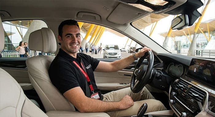 Conductor profesional de Valet Barajas uniformado y sonriente al volante de un veh&iacute;culo de gama alta.