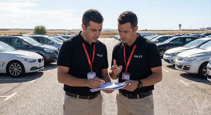 Dos operarios de Valet Barajas uniformados revisando y firmando el protocolo de estado de un veh&iacute;culo en el parking.
